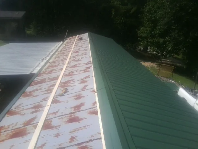 Old rusted panels beside newly installed green metal roofing — Wind Damage Roof Repair by Roofing Brothers in Franklin